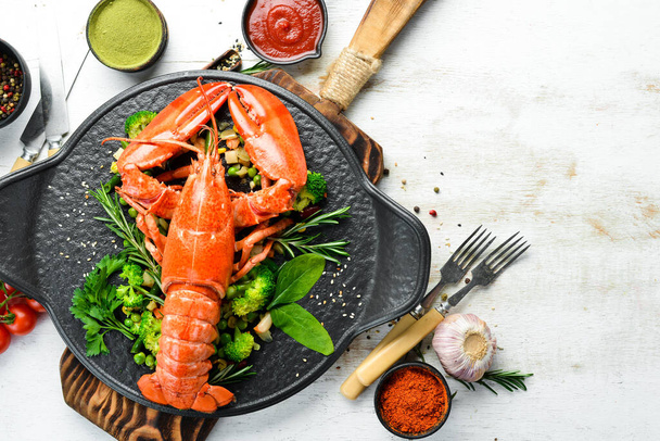 Boiled lobster with vegetables on a black stone plate. Seafood. Top view. Free space for your text. - Fotografie, Obrázek