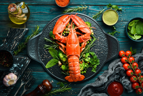 Boiled lobster with vegetables on a black stone plate. Seafood. Top view. Free space for your text. - 写真・画像