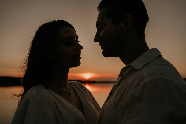 Молода пара приймає на узбережжі заходу сонця. Два силуети проти сонця. Романтична історія кохання
. - Фото, зображення