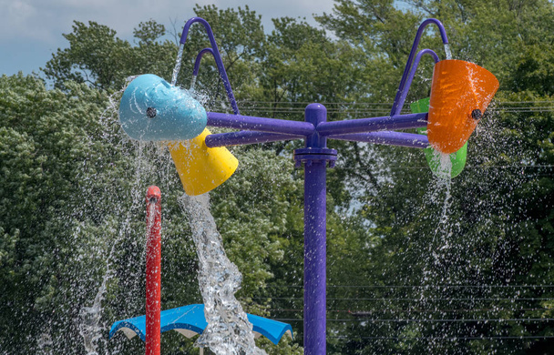 Kleurrijke emmers vullen met water voordat het legen op gelukkige kinderen, in een spatwaterpark van een kind in Indiana Usa - Foto, afbeelding