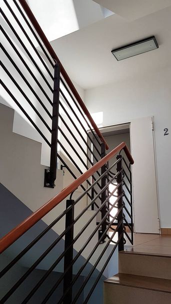 Lviv, Ukraine - 2 2 2020: A staircase with forged cast-iron railings in a modern building illuminated with light from the windows. Interior staircase and escape route during a cataclysm. The design of - Фото, изображение
