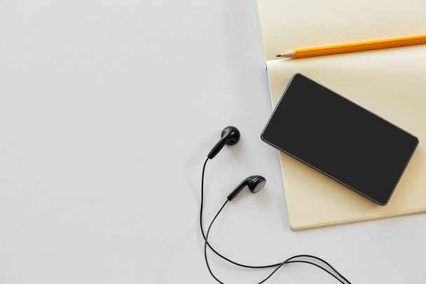earphones, smartphone and notebook with pencil - Zdjęcie, obraz