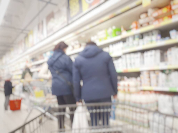 Women are standing at the shelf in the store and talking about the high prices of products. Blurred background interior of the store. - Photo, Image