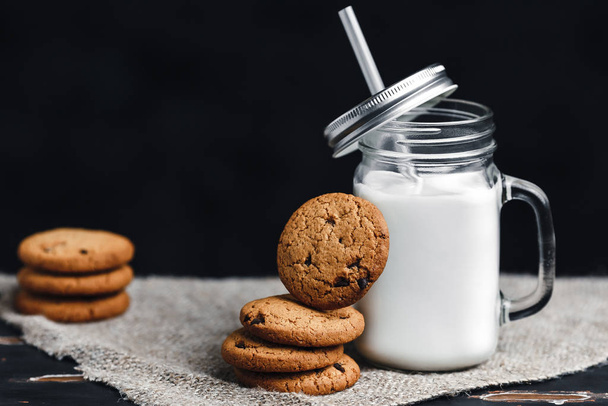 chocolate oatmeal cookies with milk on a dark background in a rustic style - Fotoğraf, Görsel