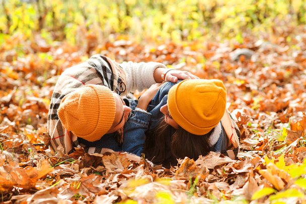 Krásný pár leží na zemi v podzimním listí. Smyslný mladý pár procházející se v podzimním parku. Romantické podzimní rande. Podzimní móda. Krásný pár těší podzim. - Fotografie, Obrázek