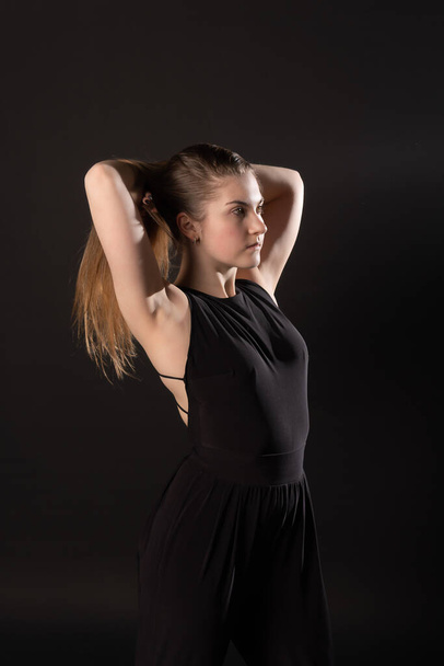 The girl holding the head on a black background in the Studio in dark clothes - Foto, Imagen