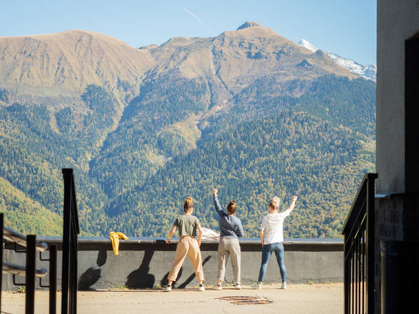 Three girls stand in different poses against the backdrop of a mountain valley - Photo, Image