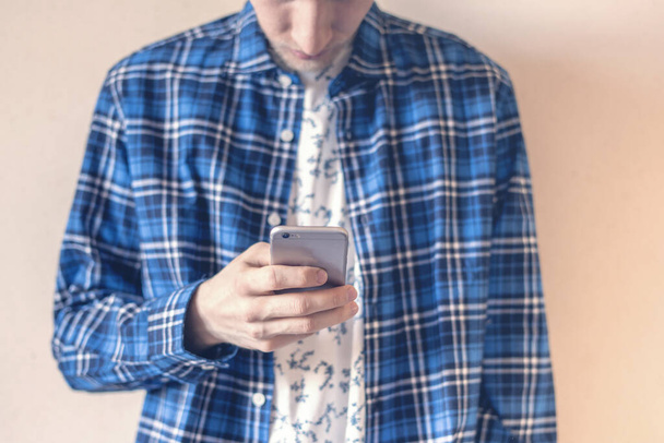 hipster casual de pie junto a la pared usando un teléfono inteligente. problemas sociales, problemas sociales personales
 - Foto, imagen