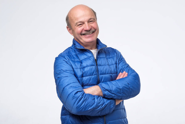 Senior man in blue jacket with crossed arms smiling - Foto, Bild