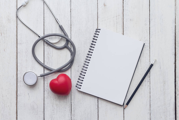 Healthy concept,red heart with stethoscope and notebook on white wood background - Foto, Imagen