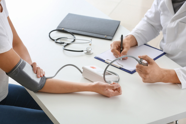 Arzt misst Blutdruck junger Frau in Klinik - Foto, Bild