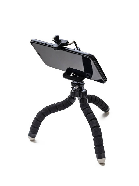 Mini trípode negro con un teléfono de color oscuro sobre un fondo blanco aislado
 - Foto, Imagen