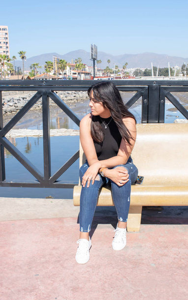 hermosa chica mexicana sentada en el muelle frente al mar
 - Foto, imagen