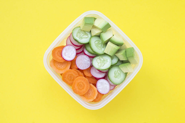 Snack vegetariano o almuerzo en la caja en el centro del fondo amarillo. Vista superior. Primer plano. Ingredientes alimentarios saludables
. - Foto, Imagen