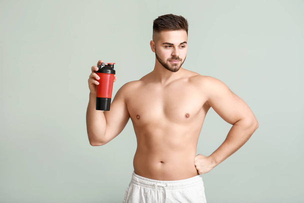 Sportlicher Mann mit Proteinshake auf hellem Hintergrund - Foto, Bild