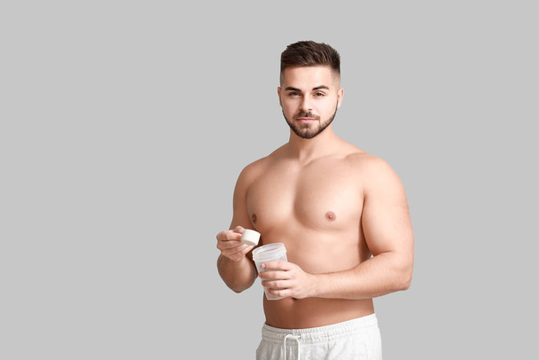 Sporty man with protein on light background - Photo, Image