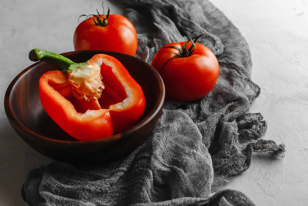 plato de madera con verduras, tomates, pimientos, cebollas con un paño sobre un fondo de hormigón ligero
 - Foto, Imagen