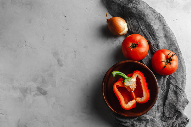 wooden plate with vegetables, tomatoes, peppers, onions with a cloth on a light concrete background - Zdjęcie, obraz