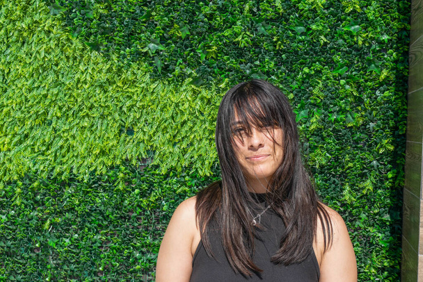 Yeşil bitki duvarının önündeki güzel Meksikalı kızın portresi. - Fotoğraf, Görsel