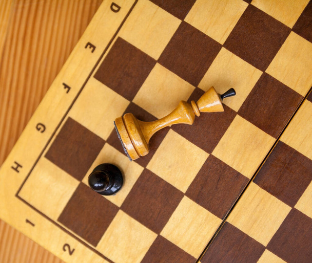 Pawn remporte une victoire sur le roi. Des pièces d'échecs en bois sur l'échiquier. Jeu d'échecs. Vue en haut. - Photo, image