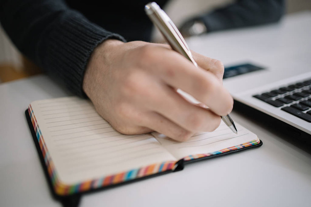 Mann macht sich Notizen und schreibt mit Stift in Notizblock - Foto, Bild