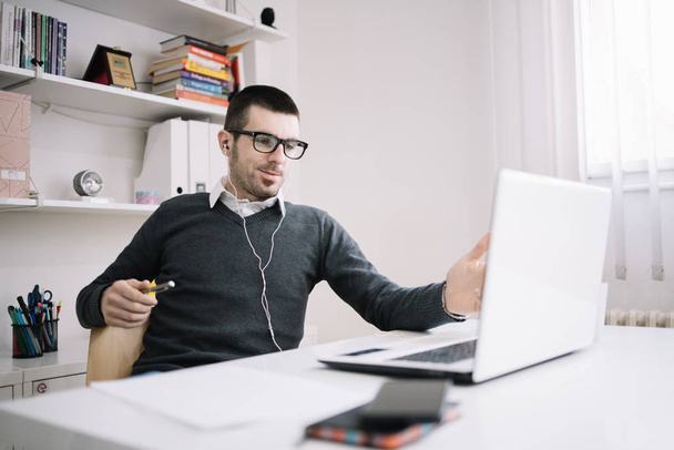 Uomo sorridente avendo una riunione online mentre seduto alla scrivania
 - Foto, immagini