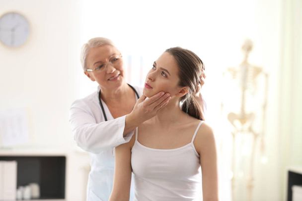 Female orthopedist examining patient's neck in clinic - Zdjęcie, obraz