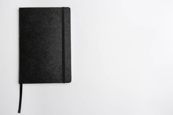 Notepad black closed with a pen top view on a white background. Space for text - 写真・画像