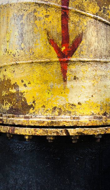Red arrow on the yellow metal surface. Yellow pipe. Direction sign. - Photo, Image
