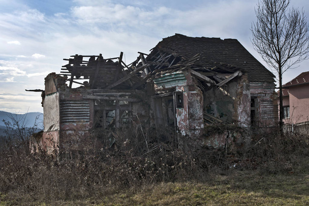 Ένα ερειπωμένο παλιό ερειπωμένο σπίτι που κατέρρευσε. - Φωτογραφία, εικόνα