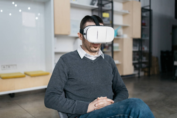Man sitting and wearing a VR glasses - Фото, изображение