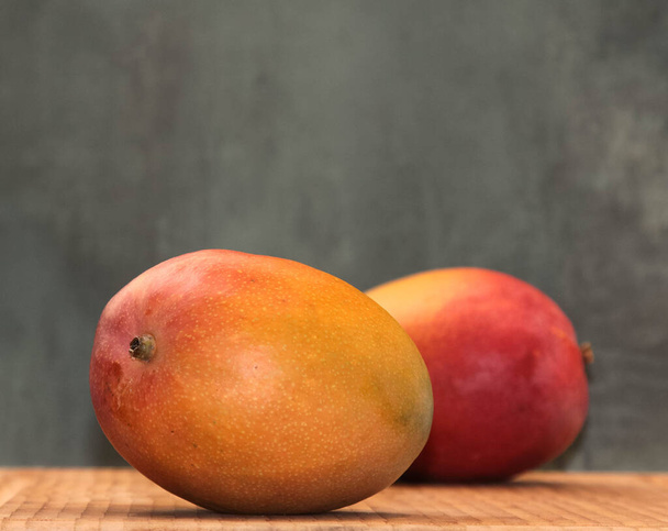  Yellow ripe mango on a red background - Foto, afbeelding