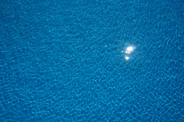 Красивое отражение солнца в голубой воде бассейна, покрытое необычными рябями от легкого ветра
. - Фото, изображение