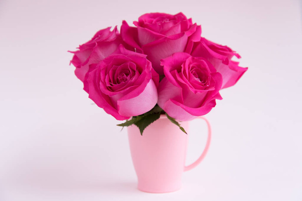 Bouquet of pink roses on a light background. A bouquet of flowers stands in a pink mug. Pink vase. Stylish bouquet. - Zdjęcie, obraz