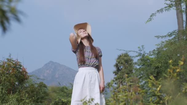 Na zewnątrz portret kobiety opalającej się na górskim tle krajobrazu. Młoda kobieta ciesząca się słońcem z zamkniętymi oczami na wsi w zwolnionym tempie. Zdrowy aktywny styl życia trekking - Materiał filmowy, wideo