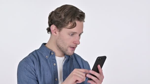 Young Man Celebrating on Smartphone, Success on White Background - Video, Çekim