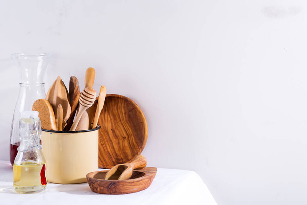Ensemble d'ustensiles de cuisine en bois dans une tasse en fer avec des assiettes en bois sur une table textile blanche. Appareils de cuisson. Zéro déchet
 - Photo, image