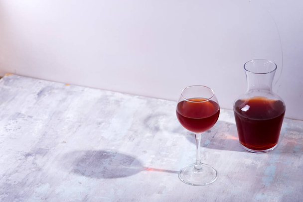 czerwone wino w kieliszku do wina i karafce z cieniami wyizolowanymi na białym kamiennym tle - Zdjęcie, obraz