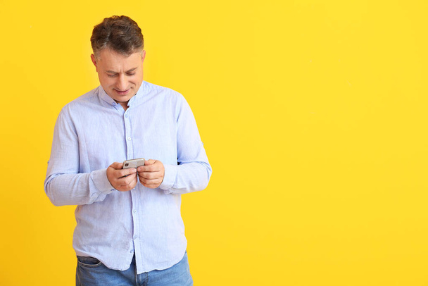 Homem maduro com telefone celular em fundo de cor
 - Foto, Imagem