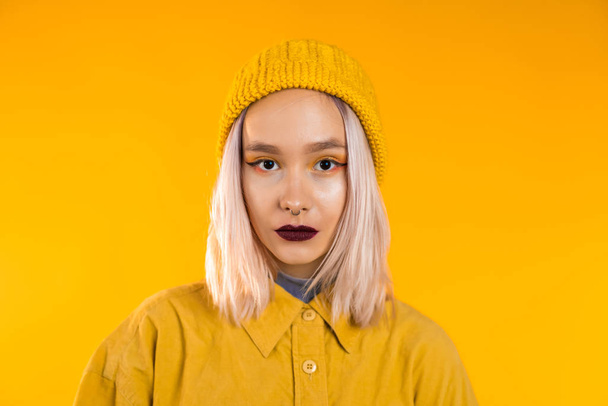 Young woman in total trendy yellow look. Portrait of beautiful punk girl with dark make-up and nose piercing on studio background. - Foto, immagini