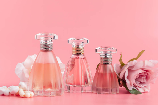 Perfume bottle with roses on pink fabric background - 写真・画像