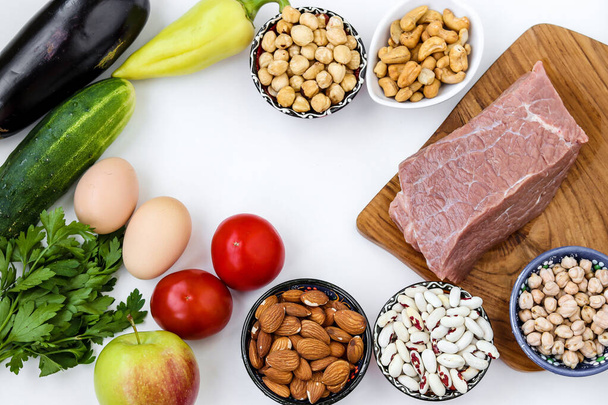 Δίαιτα ευκαμψίας με φρέσκα λαχανικά, ωμό κρέας, αυγά, όσπρια, ξηρούς καρπούς, φρούτα σε λευκό φόντο, top view, Closeup - Φωτογραφία, εικόνα