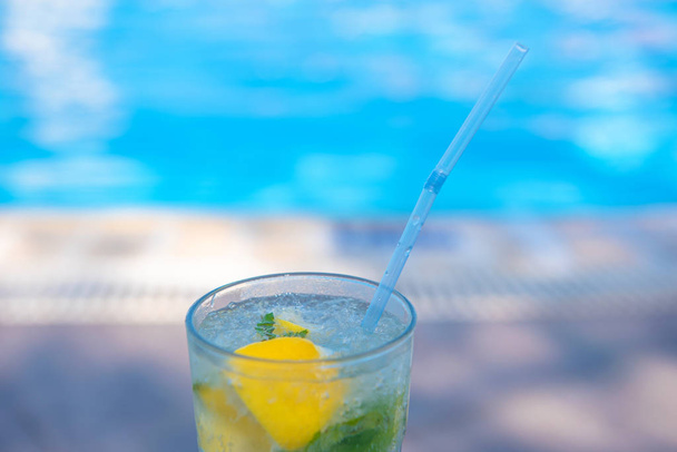 Fresh Mojito Cocktail at the edge of the resorts pool in summer. Luxury vacation concept, a place for text - Photo, Image