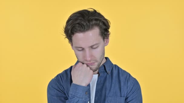 Zmęczony młody człowiek budzi się z drzemki na żółtym tle - Materiał filmowy, wideo