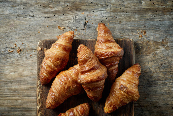 freshly baked croissants on old wooden kitchen table, top view - Photo, Image
