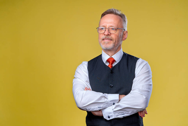 Confident middle aged man in shirt with crossed arms on his chest over yellow background - Foto, Imagem