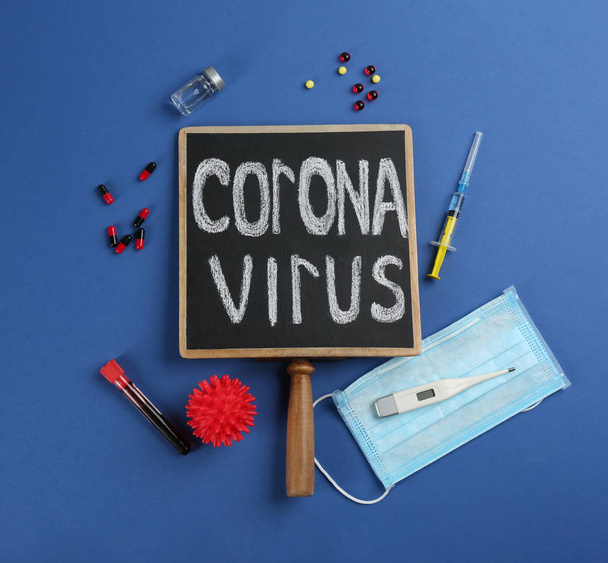 Chalkboard with words CORONA VIRUS, test tube and syringe on blue background, flat lay - Foto, afbeelding