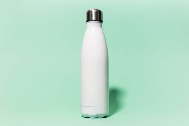 Primer plano de acero reutilizable blanco botella de agua termo inoxidable aislado en el fondo de aqua menthe color. Libre de plástico
. - Foto, imagen