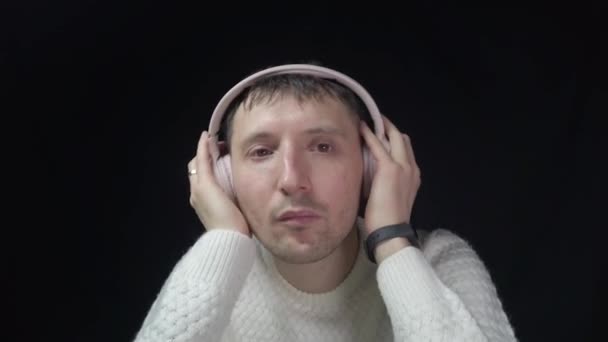 Ein Mann hört Musik in rosa Kopfhörern vor schwarzem Hintergrund - Filmmaterial, Video