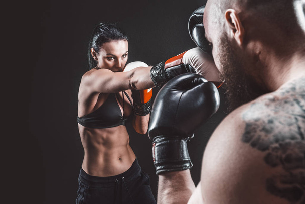 Shirtless Woman exercising with trainer at boxing and self defense lesson, studio, smoke on background. Female and male fight - Foto, Imagen
